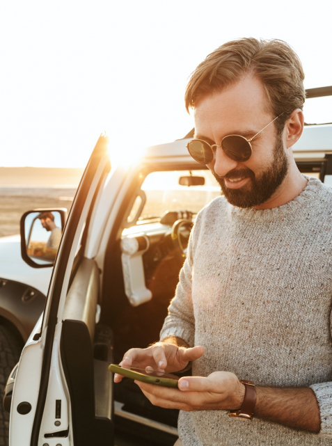 Smiling handsome young man using mobile phone